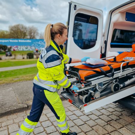 Rettungssanitäterin zieht Trage aus KTW