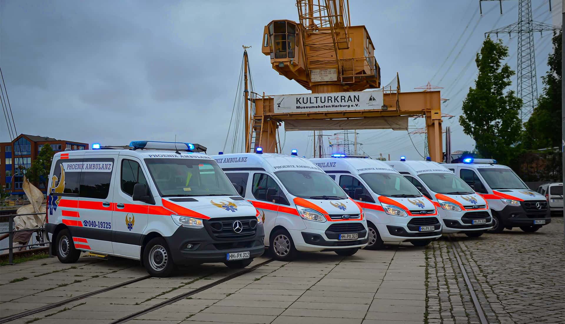 Flotte an Krankenwagen der Phoenix Ambulanz vor einem Kran am Wasser